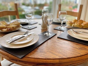 A dining table set with plates, cutlery, and glasses, with a window view in the background. - County Retreat Apartment (Whitby)