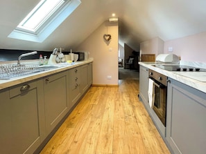 A modern kitchen with a skylight, wooden flooring, and a view into the adjacent living area. - 1 bedroom accommodation in Whitby (Whitby)