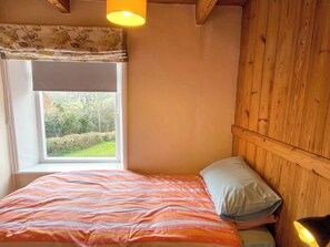 A bedroom with a bed, a window with a view of greenery, and a wooden wall. - 3 bedroom accommodation in Fylingthorpe (Fylingthorpe)