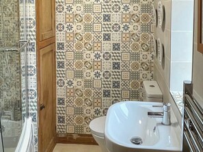 A bathroom with a tiled wall, a sink, and a toilet. - 3 bedroom accommodation in Fylingthorpe (Fylingthorpe)