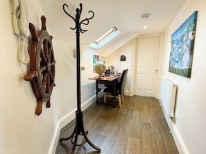 A hallway with a coat stand, a globe, a desk with a chair, and a painting on the wall. - 2 bedroom accommodation in Whitby (Whitby)