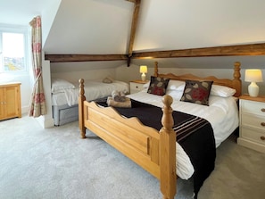 A bedroom with a wooden four-poster bed, two bedside tables with lamps, a window with curtains, and a view of the outside. - 2 bedroom accommodation in Whitby (Whitby)