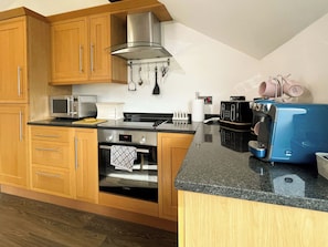 A kitchen with wooden cabinets, a Bosch oven, a microwave, a toaster, and a coffee machine. - 2 bedroom accommodation in Whitby (Whitby)
