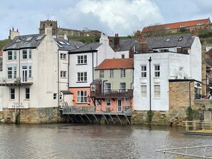 Um edifício à beira-mar com uma placa que diz 'VENIS TRADING' e uma ponte sobre a água.