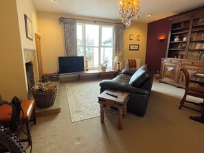 A living room with a sofa, a television, a fireplace, and a bookshelf. - 1 bedroom accommodation in Whitby (Whitby)
