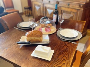 A dining table with a loaf of bread, a butter dish, a plate with pastries, a wine bottle, and glasses. - 1 bedroom accommodation in Whitby (Whitby)
