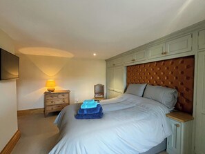 Quarto com cama, mesa de cabeceira, abajur e guarda-roupa.