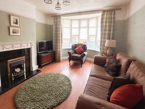 A living room with a fireplace, television, sofa, and a view of the outdoors. - 3 bedroom accommodation in Whitby (Whitby)