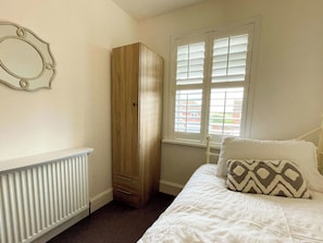 A bedroom with a bed, a wardrobe, a radiator, and a window with blinds. - 3 bedroom accommodation in Whitby (Whitby)