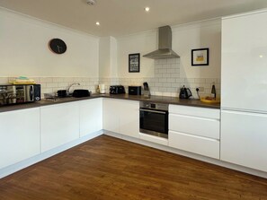 A modern kitchen with white cabinets, a stainless steel oven, a microwave, and a toaster. - 2 bedroom accommodation in Whitby (Whitby)