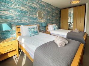 A hotel room with two beds, wooden headboards, a large mirror, and a wardrobe. - 2 bedroom accommodation in Whitby (Whitby)