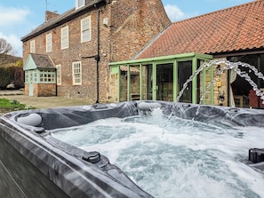 A hot tub with water jets in front of a brick building with a green glass enclosure. - The Farmhouse - UKC9936 (Gateshead)