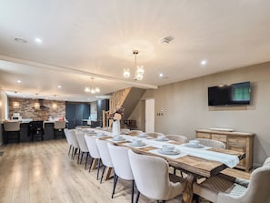A modern dining area with a long table set for six, surrounded by white chairs with black legs. - The Farmhouse - UKC9936 (Gateshead)