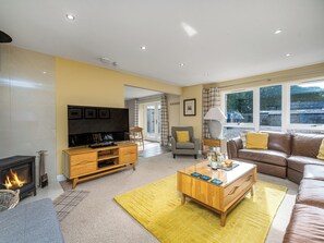 A living room with a fireplace, sofa, coffee table, and a television. - The Gardener's Cottage - UKC6966 (Carnoustie)