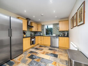 A modern kitchen with a stainless steel refrigerator, wooden cabinets, a microwave, and a dishwasher. - The Gardener's Cottage - UKC6966 (Carnoustie)