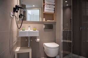 A modern bathroom with a white sink, toilet, and glass shower enclosure. - MH Apartments Plaza Europa (L'Hospitalet de Llobregat)