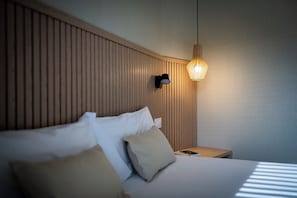A hotel room with a bed, pillows, a nightstand, a wall-mounted lamp, and a wooden headboard. - MH Apartments Plaza Europa (L'Hospitalet de Llobregat)