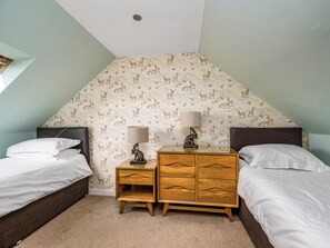 A bedroom with two beds, a nightstand, a dresser, and a patterned wallpaper. - The Carriage House - UKC6967 (Carnoustie)