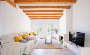Ein modernes Wohnzimmer mit einer Couch, Fernseher, Kamin und großen Fenstern.
