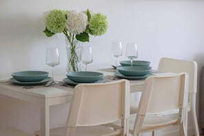 A dining table set with teal bowls, wine glasses, and a vase with flowers. - Warsaw | Zwycięzców 40 | Comfortable Apartment | Remote Work (Warszawa)