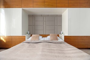 Ein modernes Schlafzimmer mit einem großen Bett, einer gepolsterten Kopfteil und integrierten Nachttischen.