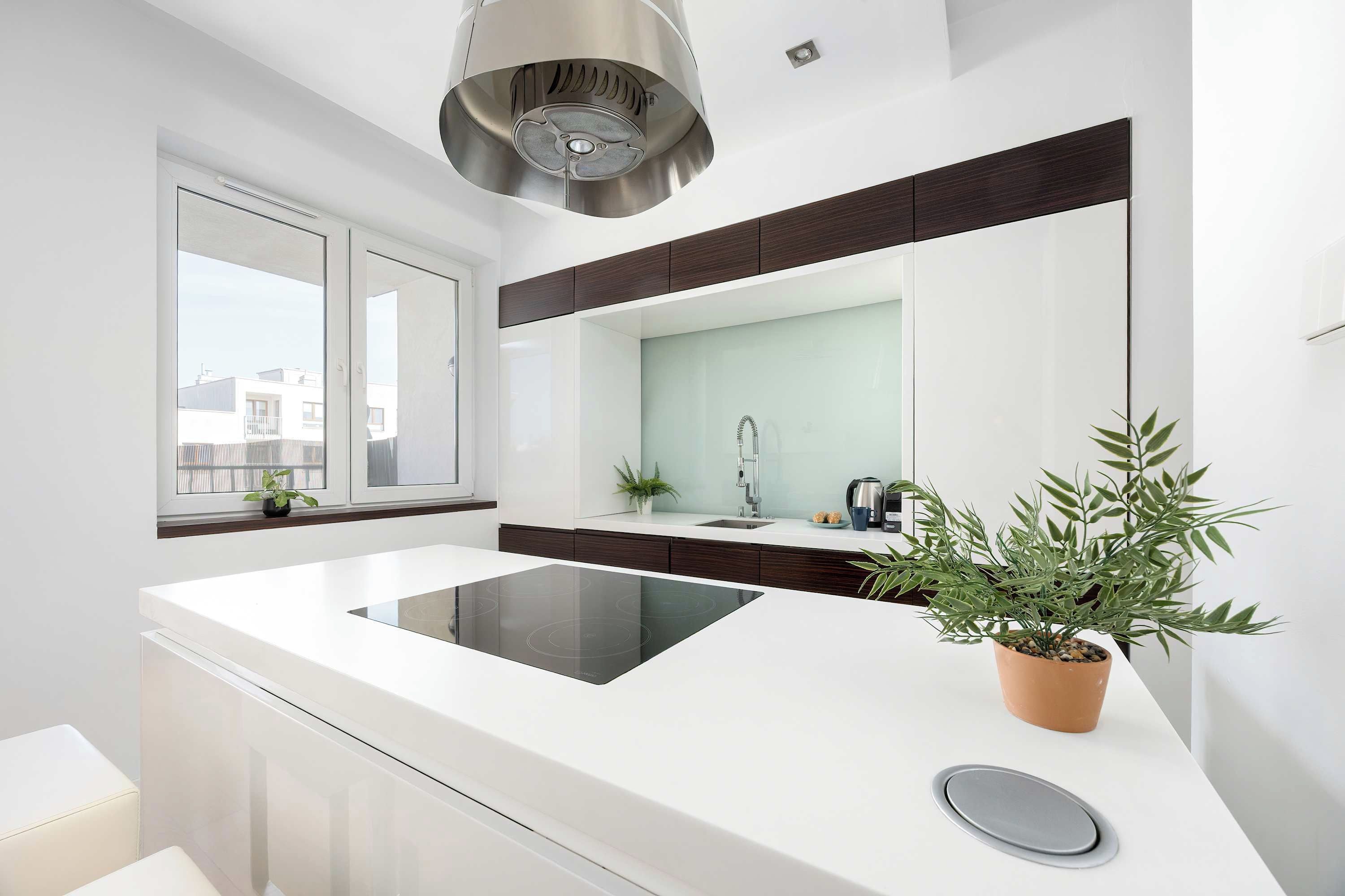 Une cuisine moderne dotée d’un îlot central, d’une cuisinière encastrée, d’un évier et d’une fenêtre donnant sur des immeubles.