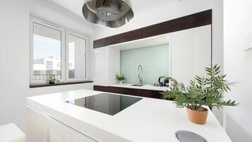 Une cuisine moderne dotée d’un îlot central, d’une cuisinière encastrée, d’un évier et d’une fenêtre donnant sur des immeubles.