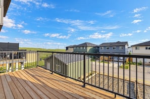 A residential area with houses, a wooden deck, and a clear sky. - Spacious and comfort| Near Airport| Easy Access to Stoney Trail & the Rockies. (calgary)