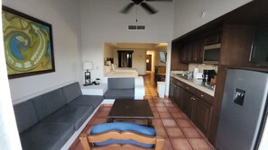 A compact hotel room with a sofa, a small table, a kitchenette, and a bed in the background. - Hacienda del Mar beautiful beachfront luxury resort in Cabo San Lucas, Mexico (Cabo San Lucas)