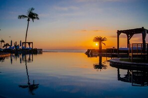 A tranquil sunset over a calm pool with lounge chairs and a wooden pergola. - Hacienda del Mar beautiful beachfront luxury resort in Cabo San Lucas, Mexico (Cabo San Lucas)