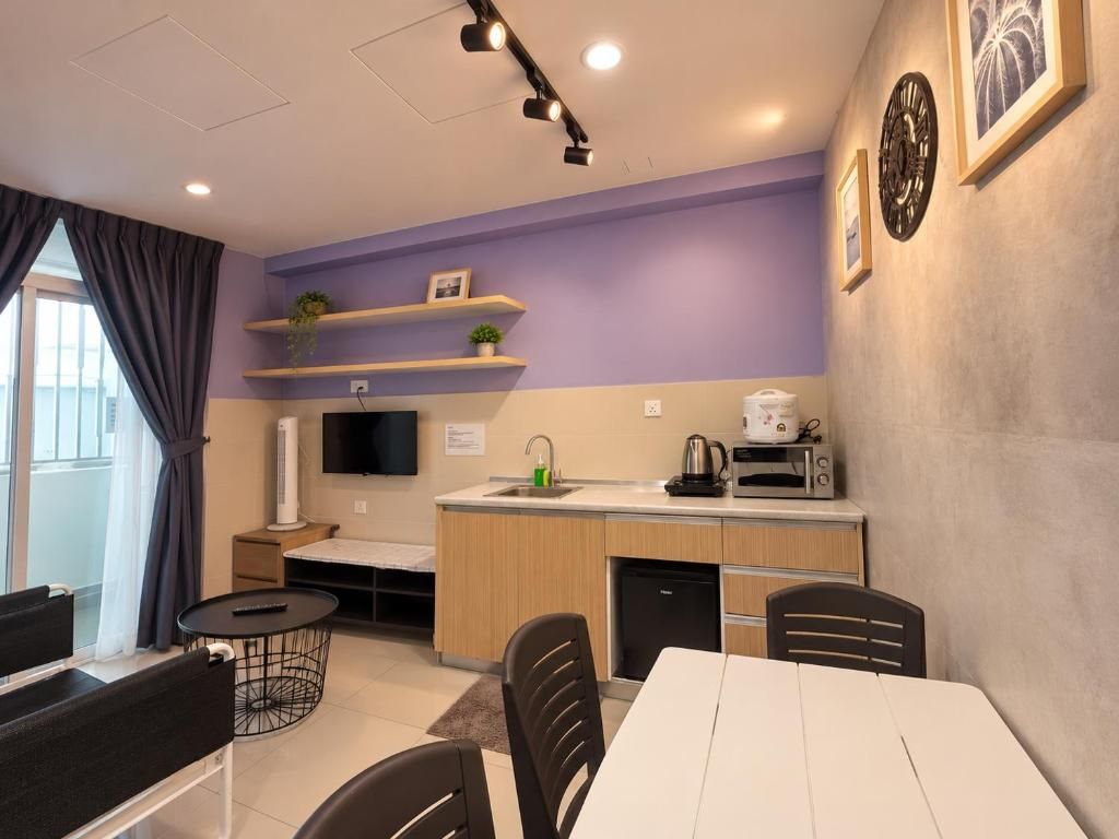 A modern kitchen with a dining area, a flat-screen TV, and a small refrigerator.