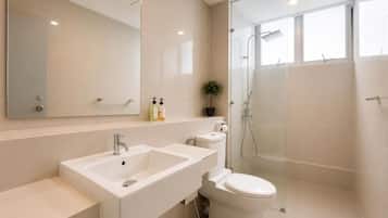 Een moderne badkamer met een grote spiegel, twee wasbakken, een toilet en een douchehoek.