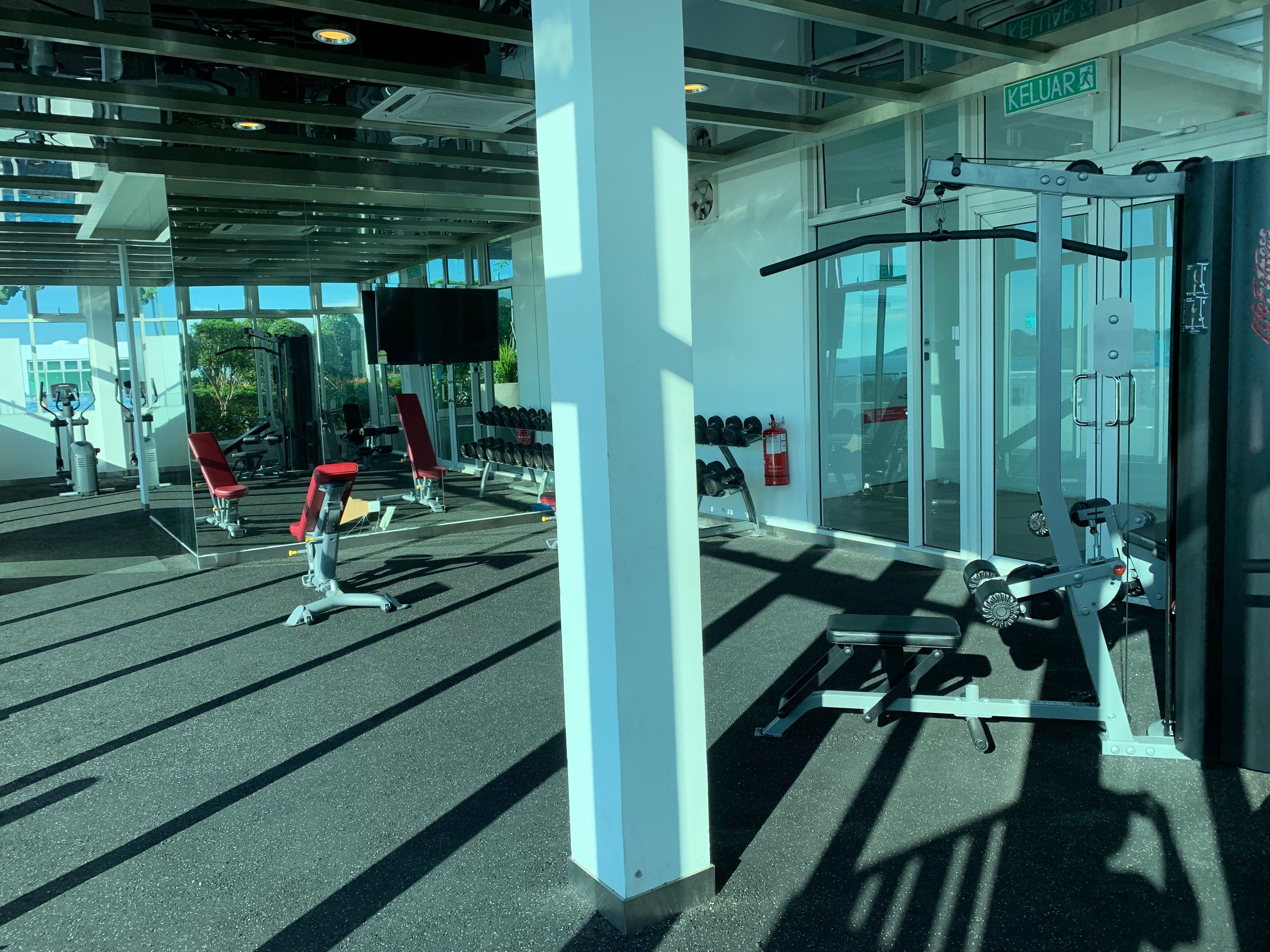 Academia com equipamentos de ginástica, televisão e extintor de incêndio.