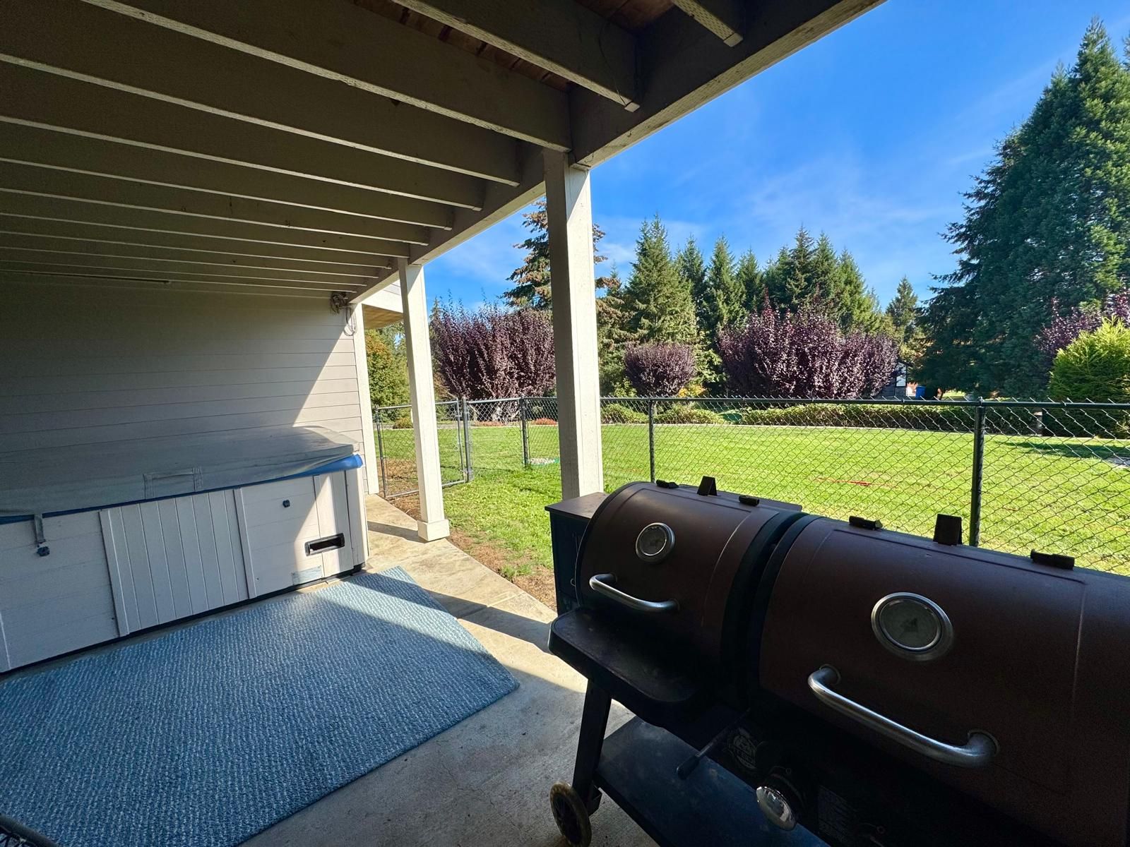 An outdoor patio with a barbecue grill and a covered seating area.