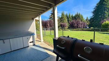 An outdoor patio with a barbecue grill and a covered seating area.