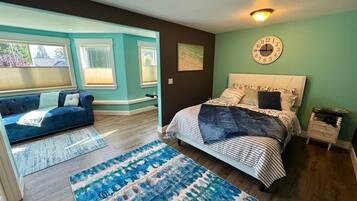 A bedroom with a bed, a sofa, a rug, and a wall clock.