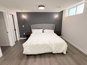 Une chambre à coucher avec un lit, des tables de chevet, une commode et une fenêtre.