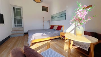 A bedroom with a bed, bedside table, and a window.