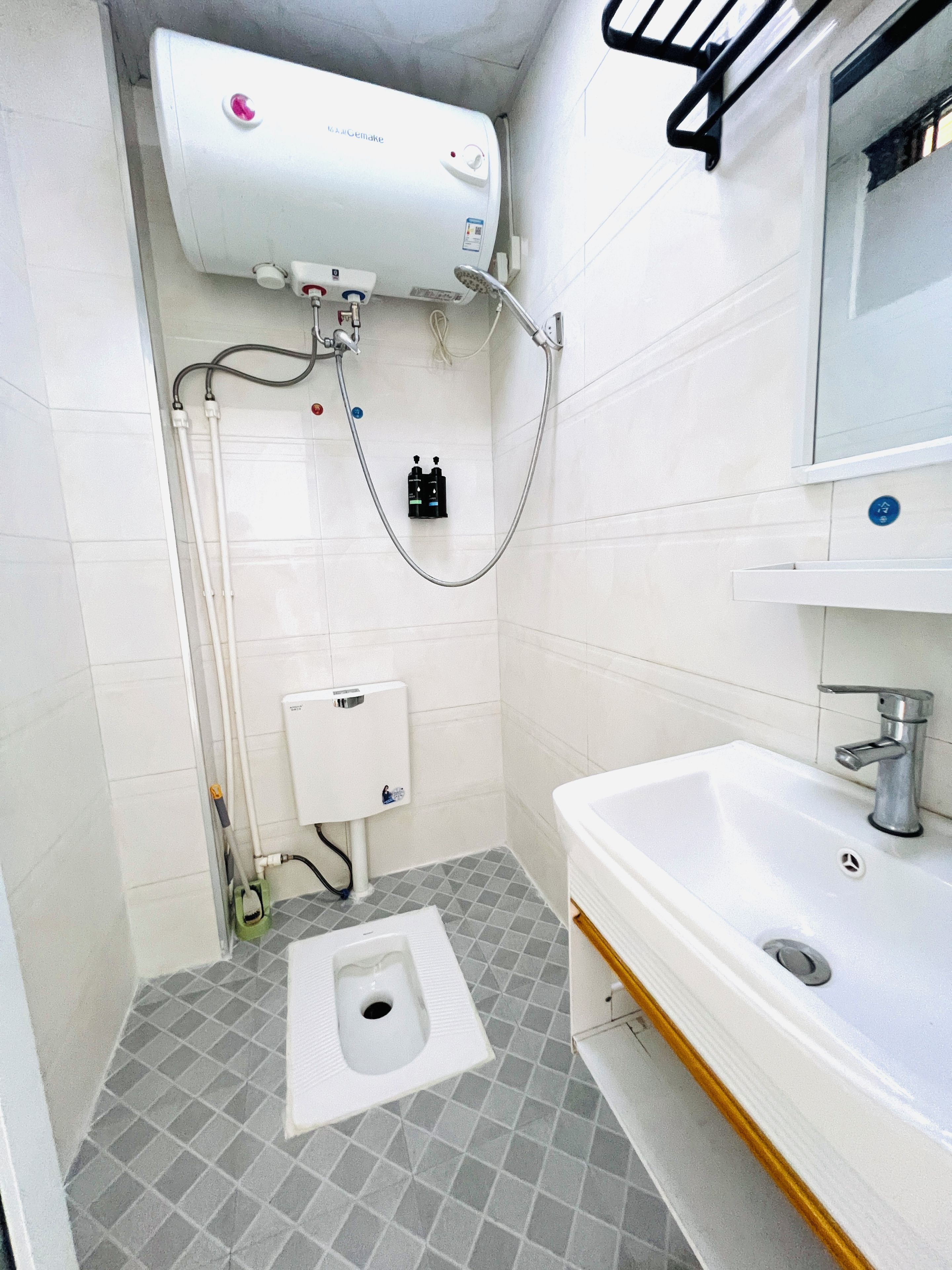 Ein kleines Badezimmer mit Toilette, Waschbecken, Spiegel und Warmwasserbereiter.