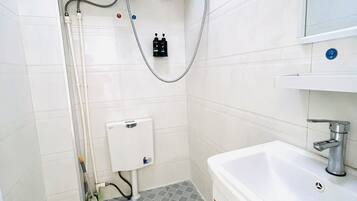 Ein kleines Badezimmer mit Toilette, Waschbecken, Spiegel und Warmwasserbereiter.