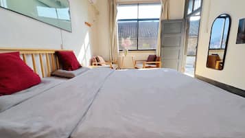 Une chambre d’hôtel avec un lit, un bureau, une chaise et une fenêtre donnant sur un paysage agréable.