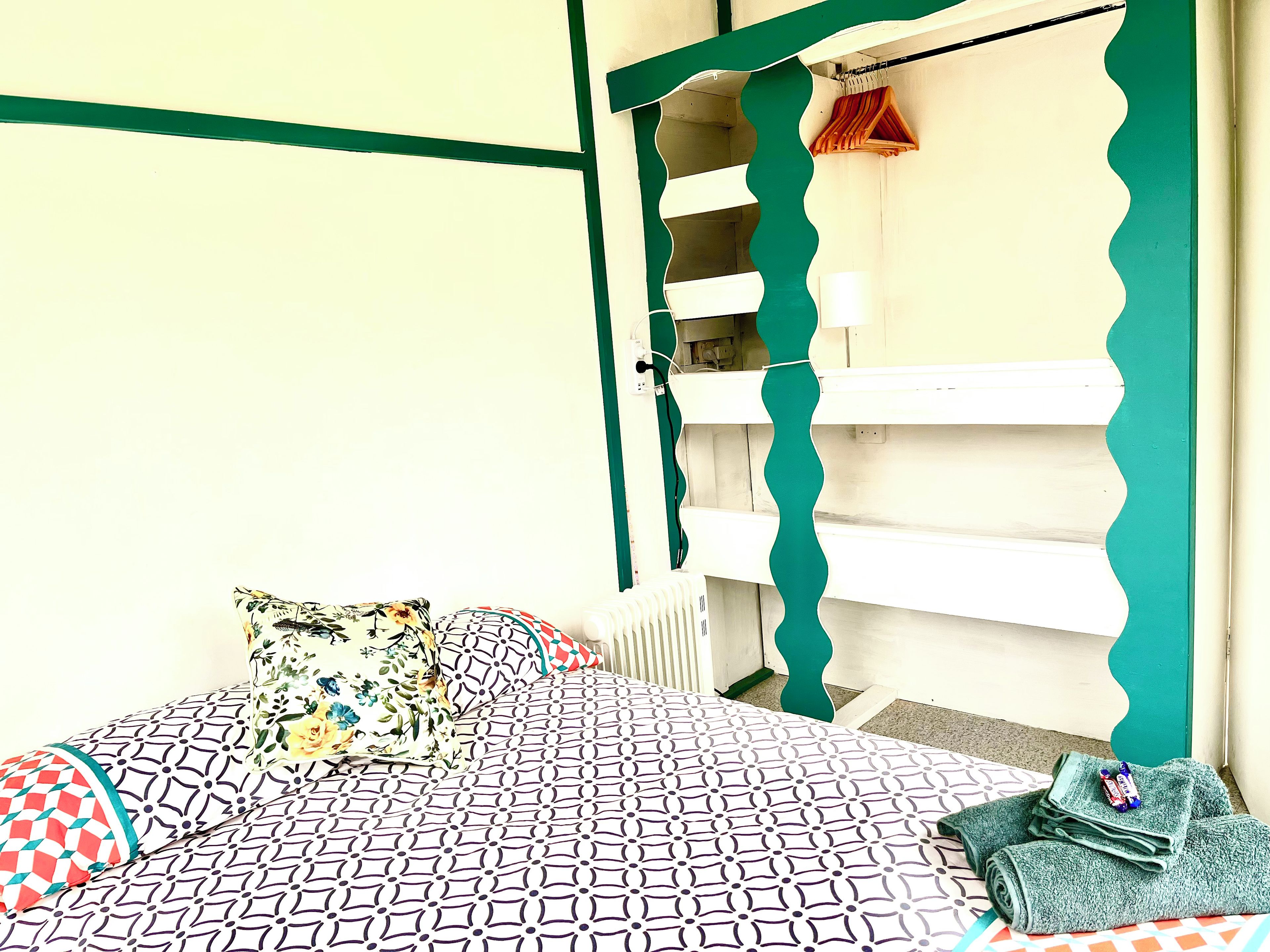 Ein Schlafzimmer mit einem Bett, Kissen, einem Heizkörper und einer grünen Tür.