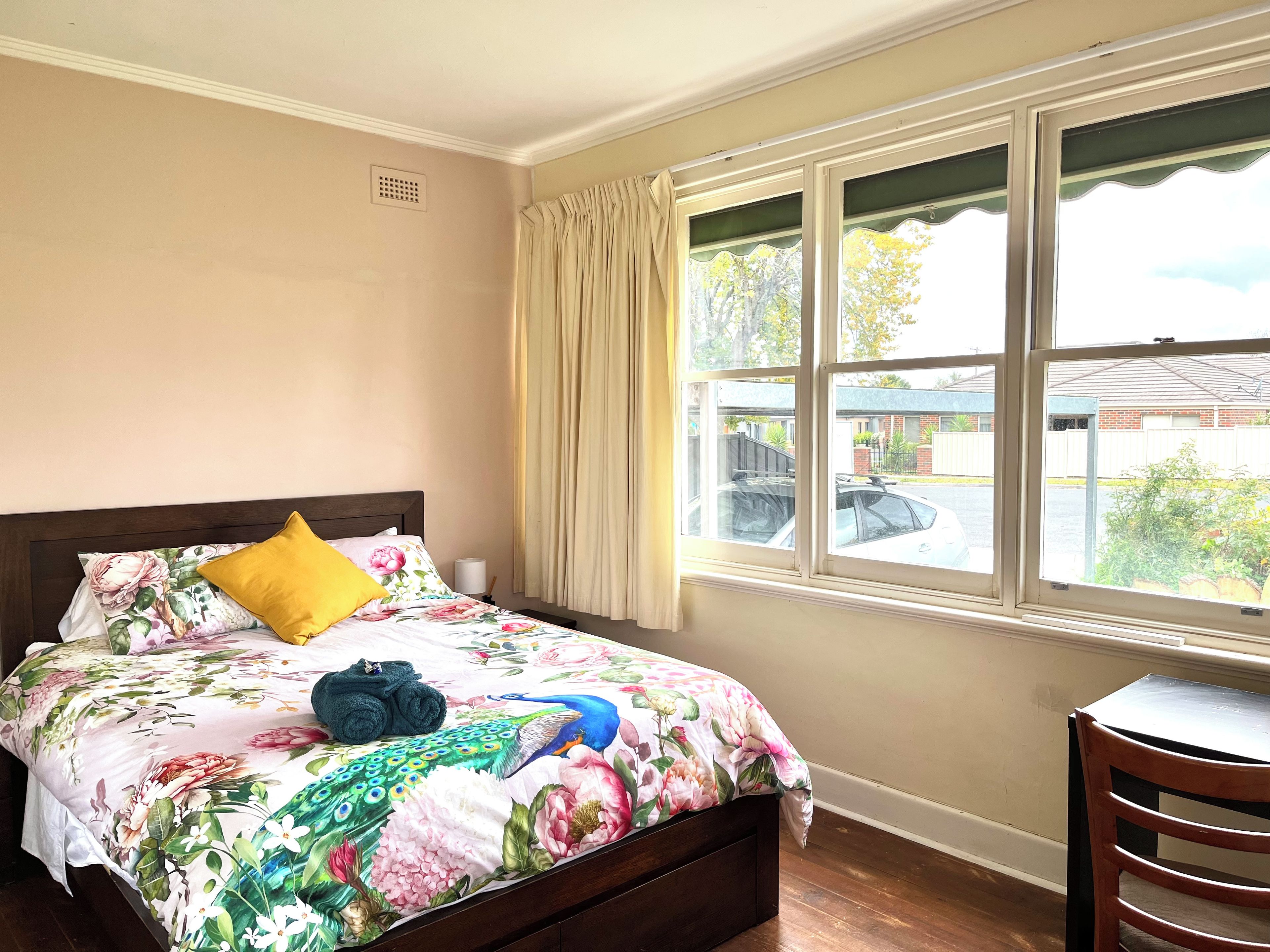 A bedroom with a bed, a window, and a chair.