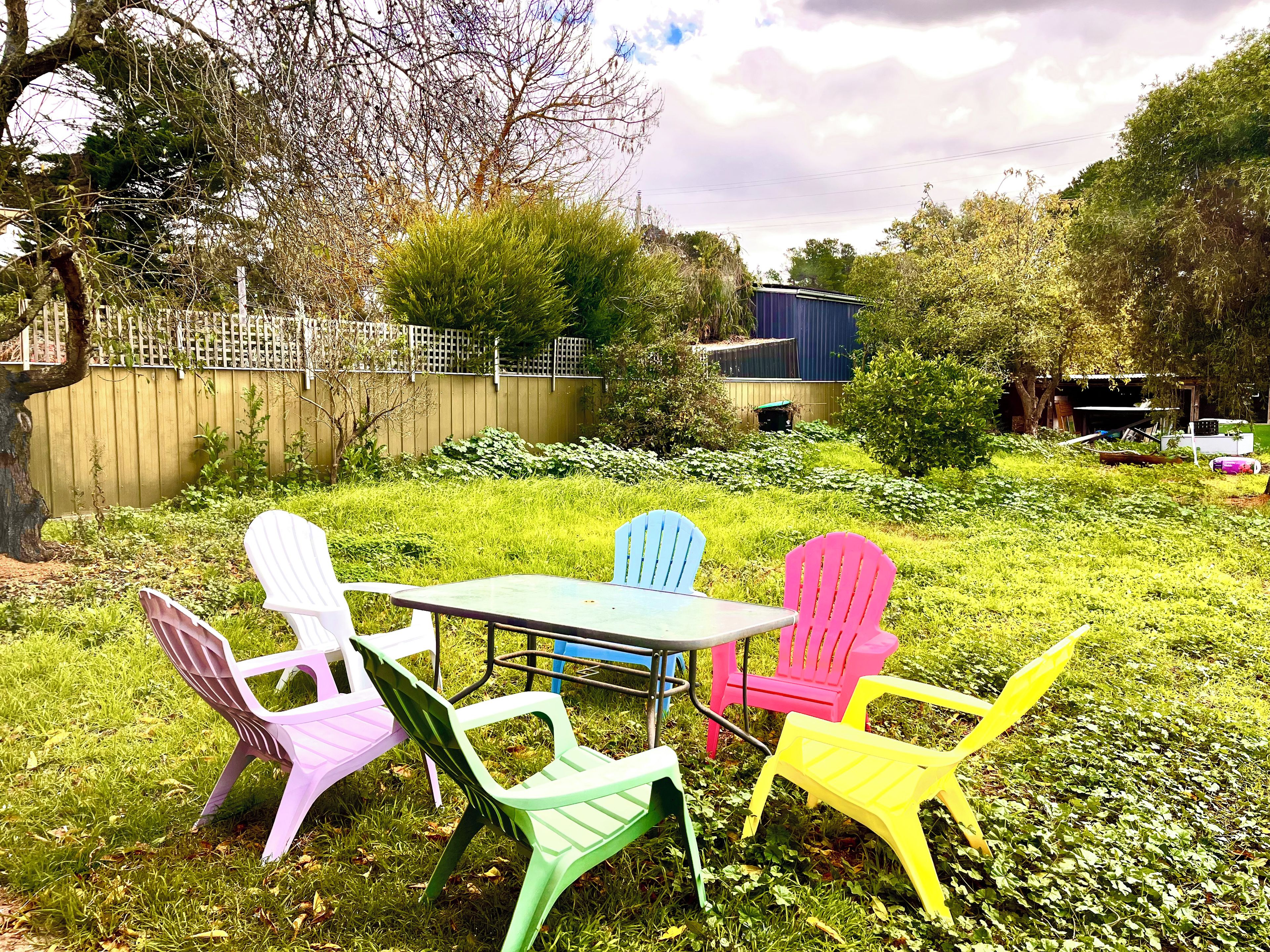 Une terrasse avec une table et des chaises en plastique de couleurs vives.