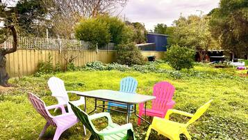 Une terrasse avec une table et des chaises en plastique de couleurs vives.