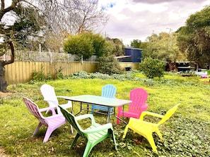 Une terrasse avec une table et des chaises en plastique de couleurs vives.