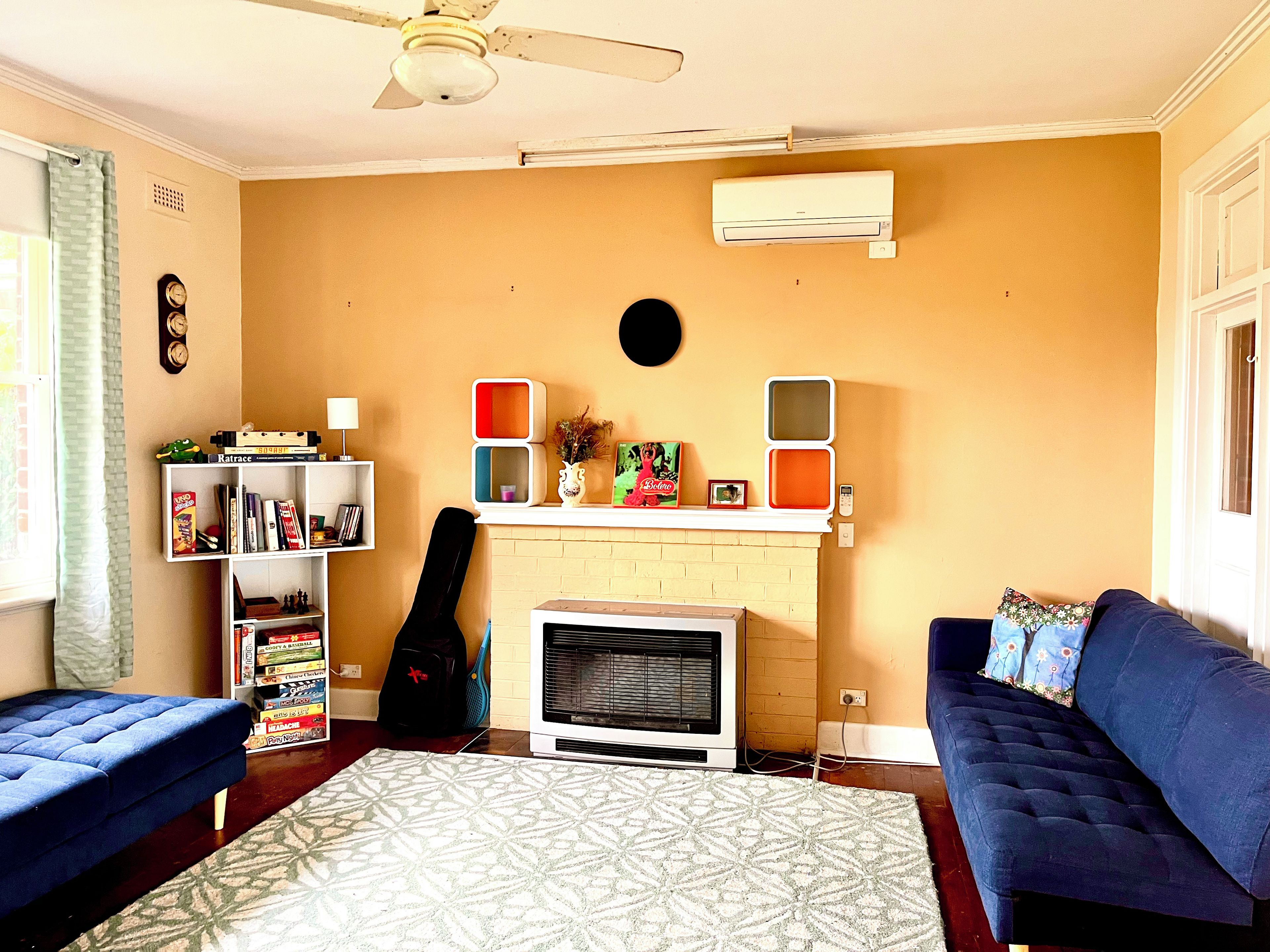 A living room with a fireplace, a bookshelf, a blue sofa, and a patterned rug.