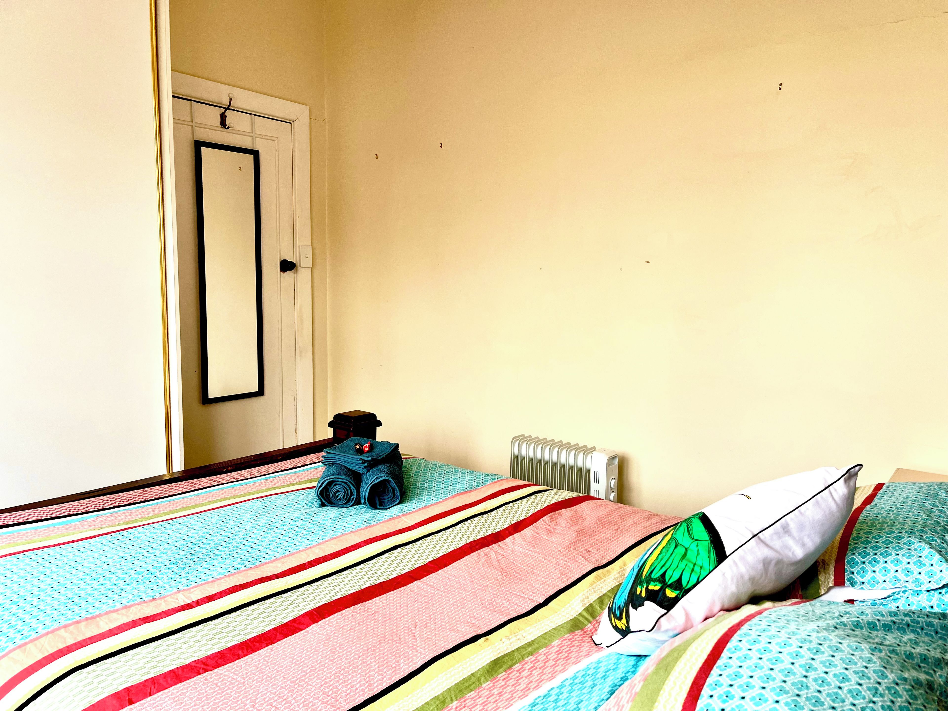 Ein Zimmer mit einem Bett, einem Heizkörper und einer Tür.