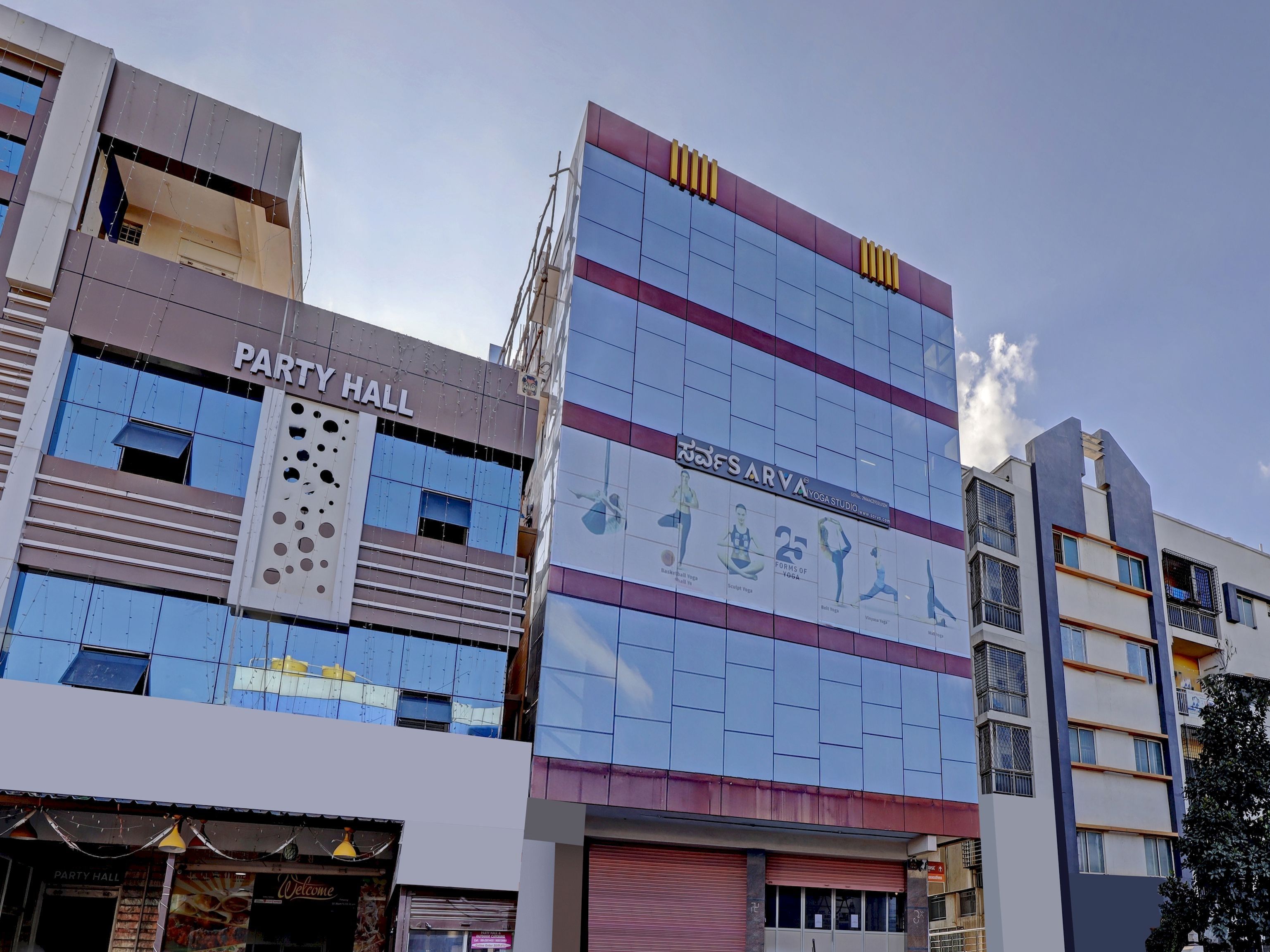 A multi-story building with a 'PARTY HALL' sign and a 'SAVYA YOGA STUDIO' sign.