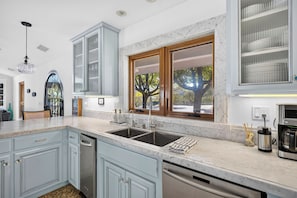 A modern kitchen with a marble countertop, stainless steel appliances, and a large window with a view of trees. - Pool + Hot Tub | Fire Pit + Hammock | Hilltop Valley Views | Vino Vista Villa (Paso Robles)